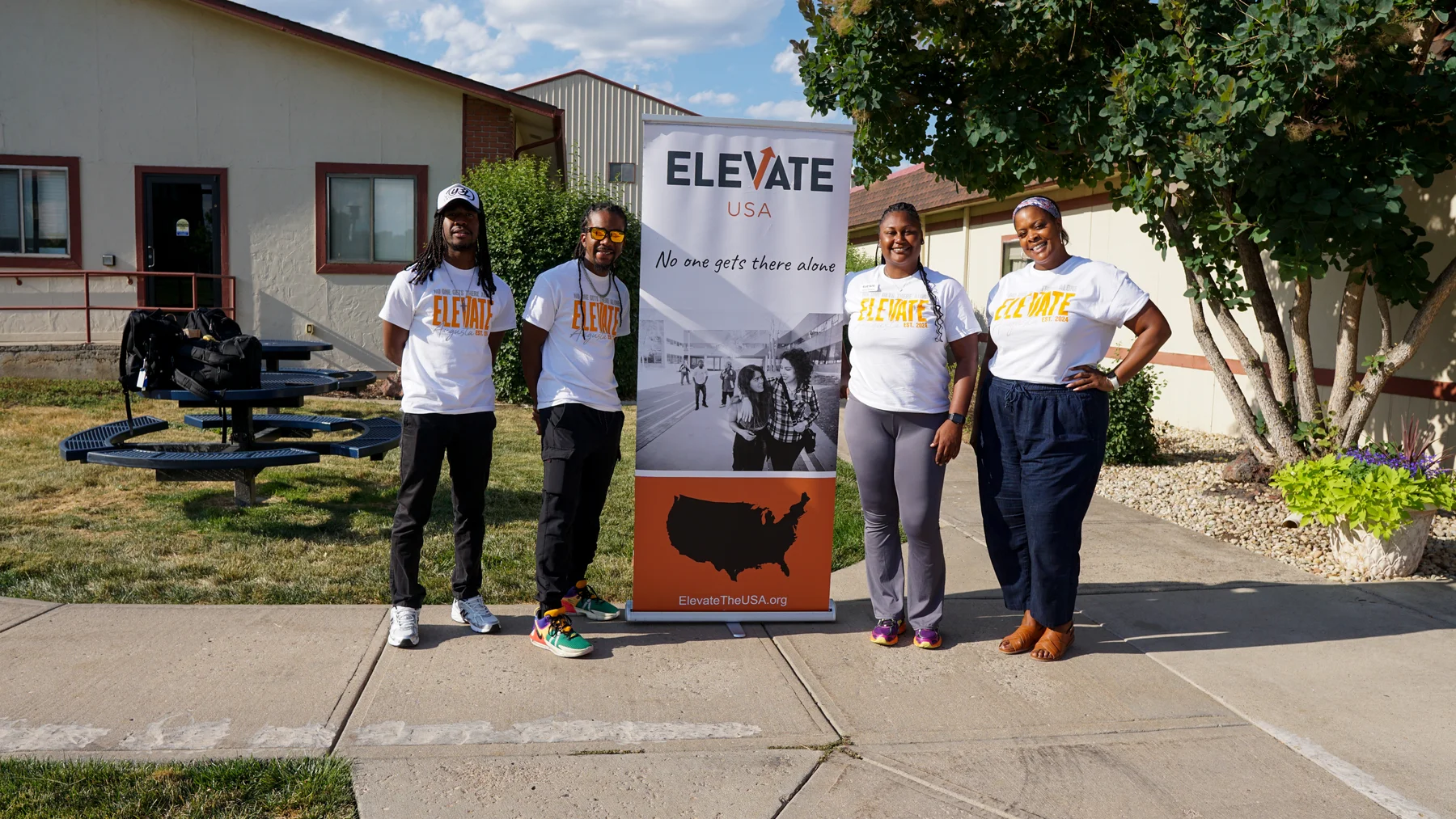 Four Elevate Augusta staff members standing together beside an Elevate USA banner